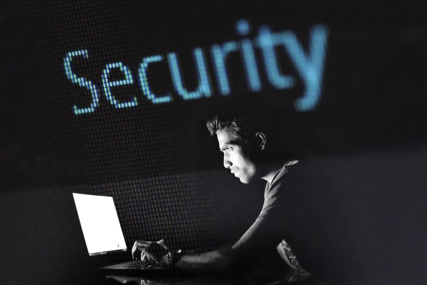 un homme devant un écran d'ordinateur surmonté du mot "sécurité" en anglais.