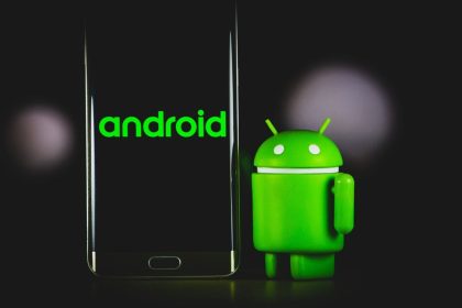 smartphone Android noir placé à côté de la mascotte Android en vert